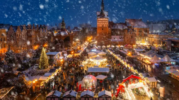 Magischer Weihnachtsmarkt-Zauber auf Advents-Flusskreuzfahrt 2026 Festlich beleuchteter Weihnachtsmarkt in einer historischen Altstadt bei nächtlichem Schneefall mit Karussell und Marktständen – ein Highlight während einer Flusskreuzfahrt in der Adventszeit.