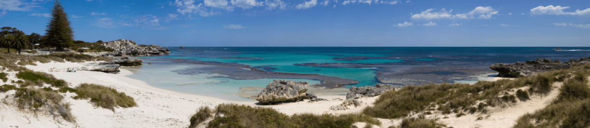 Panorama von Basin Beach mit weißem Sand und türkisfarbenem Meer.