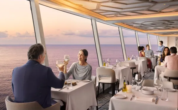 Spezialitätenrestaurant Palomar Ein Paar trinkt Wein im Restaurant Palomar an Bord von NCL Prima. Im Hintergrund sieht man das Meer.