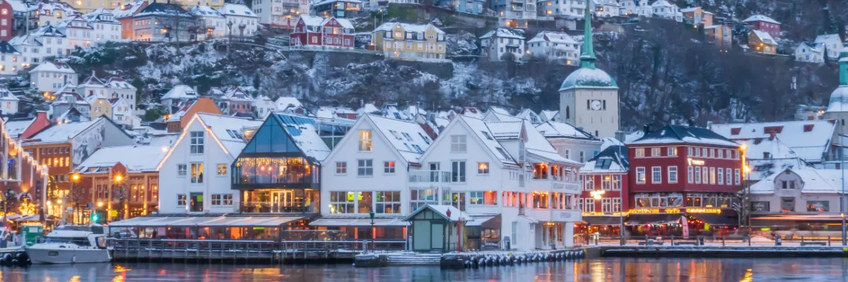 Winterzauber in Bergen – Highlights der Norwegen-Kreuzfahrt Schneebedeckte, farbenfrohe Holzhäuser am Kai von Bergen in Norwegen während einer winterlichen Nordland-Kreuzfahrt.
