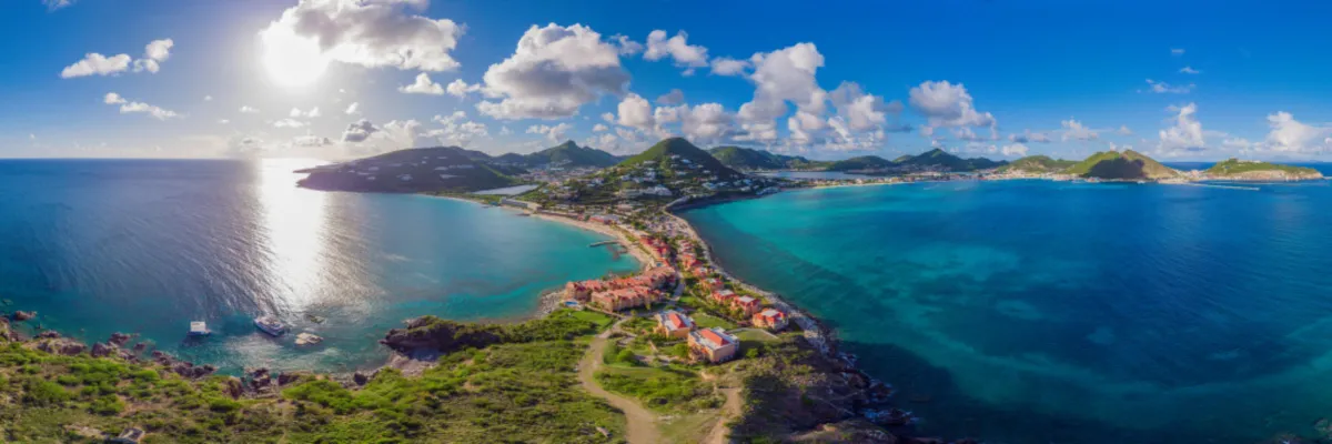 Karibisches Inselparadies – Traumziele im TUI Cruises MEER SALE 2026 Spektakuläre Panorama-Aussicht auf eine tropische Karibikinsel mit tiefblauem und türkisbecken Wasser, grünen Hügeln und einer schmalen Landzunge im Sonnenlicht.