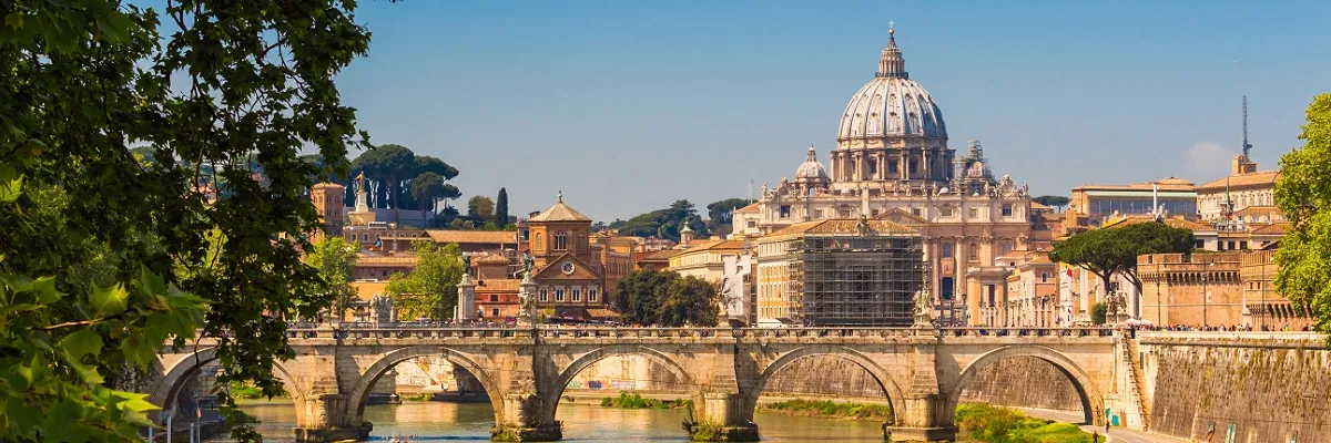 Mittelmeer-Kreuzfahrten mit Kabinenupgrade Blick auf den Petersdom in Rom und eine Brücke über den Tiber.