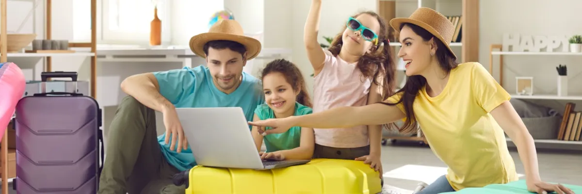 AIDA Familien-Special von Hamburg Eine vierköpfige Familie mit zwei Kindern, die sich gemeinsam auf den Urlaub vorbereitet. Sie stehen mit gepackten Koffer zusammen und schauen zusammen das Laptop.
