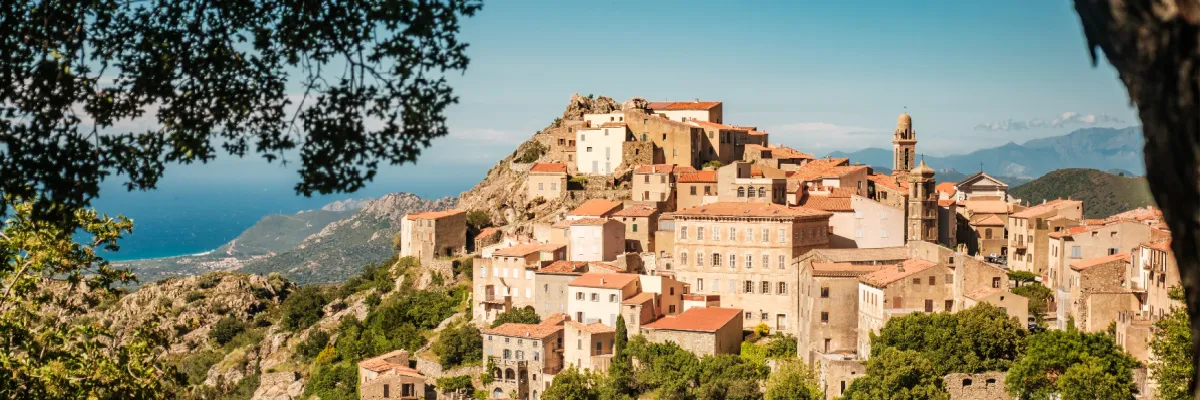 AIDA Last Minute 2026: Mediterrane Schätze, historische Gassen und sonnengeküsste Küsten im Westmittelmeer entdecken Ein malerisches Bergdorf auf Korsika mit Blick auf das azurblaue Meer während einer AIDA Last Minute 2026 Kreuzfahrt durch das Mittelmeer.
