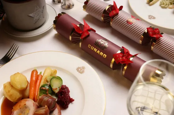 Cunard Festtagsreise – Britische Weihnachtstraditionen und kulinarisches Festmenü an Bord Festlich gedeckter Tisch an Bord eines Cunard Schiffes mit britischen Knallbonbons und einem feierlichen Weihnachtsmenü.