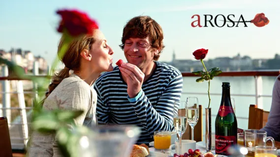 Paar genießt romantisches Frühstück mit Champagner auf dem Sonnendeck einer A-ROSA Flusskreuzfahrt.