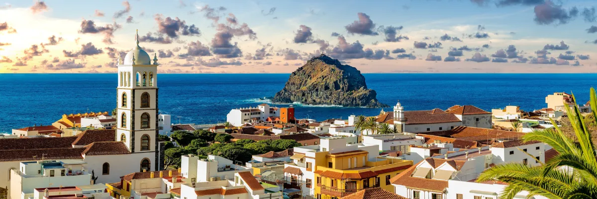 AIDA Kanaren Kreuzfahrt – Küstenpanorama Teneriffa Garachico Malerisches Panorama von Garachico auf Teneriffa mit historischem Kirchturm, kanarischen Häusern und dem charakteristischen Felsen im blauen Atlantik.