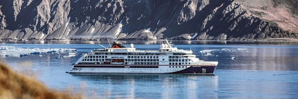 Hapag-Lloyd Cruises: Luxus-Expeditionsschiff der HANSEATIC class in nordamerikanischen und arktischen Gewässern Expeditionsschiff der HANSEATIC class von Hapag-Lloyd Cruises vor einer imposanten Berg- und Fjordkulisse mit treibendem Eis.