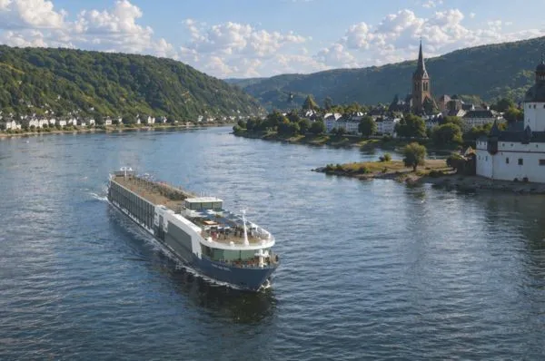 Thurgau Avanti entdecken Blick über das Schiff Thurgau Avanti im Fluss. Im Hintergrund sind Gebirge und eine Kirche zu sehen.