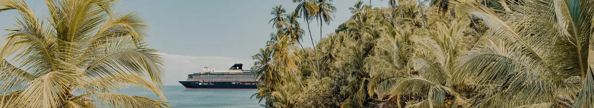 An einem karibischen Sandstrang mit Palmen, hält EXPLORA III, das neueste Schiff von Explora Journeys.