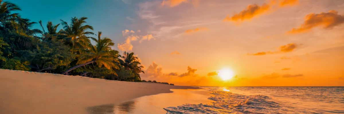 Ein warmer Sonnenuntergang am Strand einer karibischen Insel. Die Wellen schwappen sanft auf das Land.
