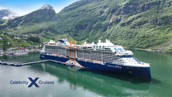 Das moderne Schiff Celebrity Apex von Celebrity Cruises liegt an einem Norwegischen Hafen an einem Steg umgeben von Bergen.