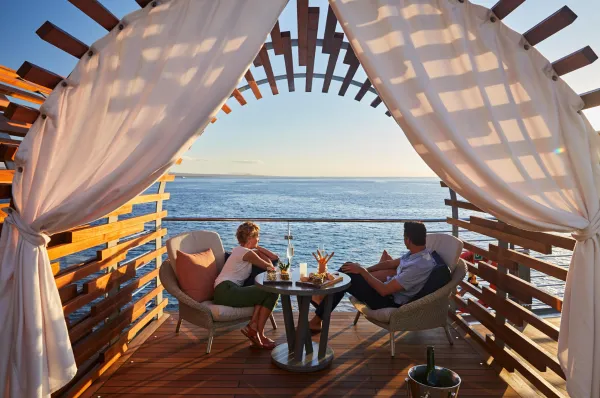 Cabana an Deck der Celebrity Flora Paar in einer Cabana an Deck der Celebrity Flora mit Sekt und Blick aufs Meer im Abendlicht.