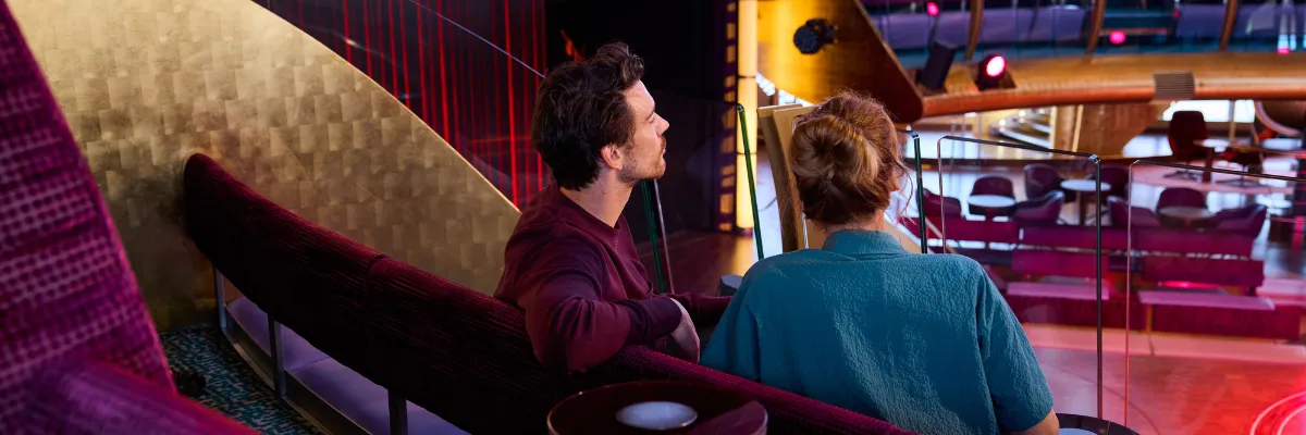Paar sitzt entspannt in den oberen Rängen des Theatriums auf AIDAluna mit Blick auf die Bühne.