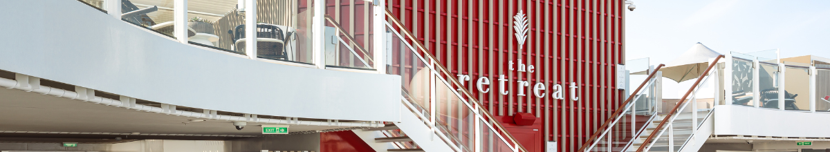 Der Außenbereich von The Retreat mit einer roten Akzentwand und zwei Treppen, die auf das untere der beiden Decks führt.