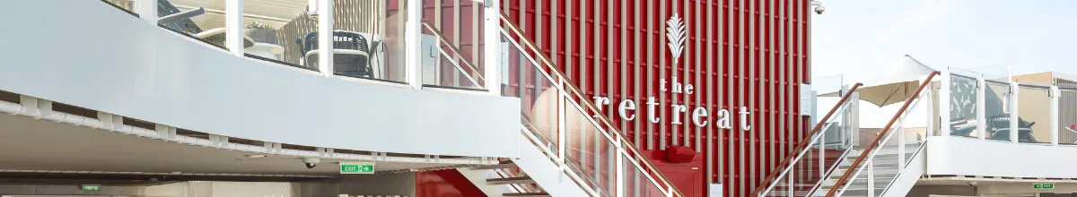 Der Außenbereich von The Retreat mit einer roten Akzentwand und zwei Treppen, die auf das untere der beiden Decks führt.