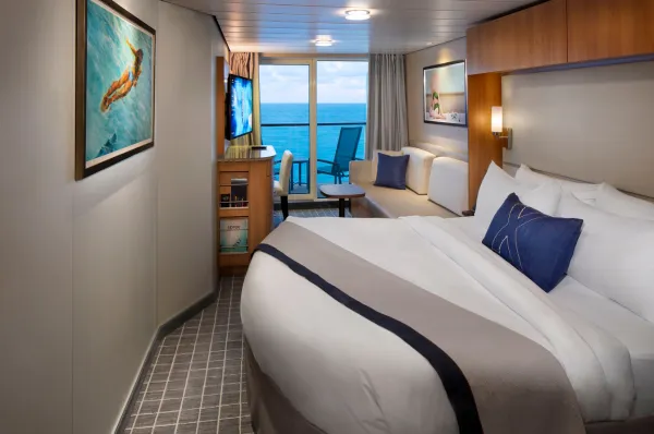 Die Concierge Class Balkonkabine auf Celebrity Equinox mit einem großen Doppelbett und tollen Panoramafenstern zum Balkon.