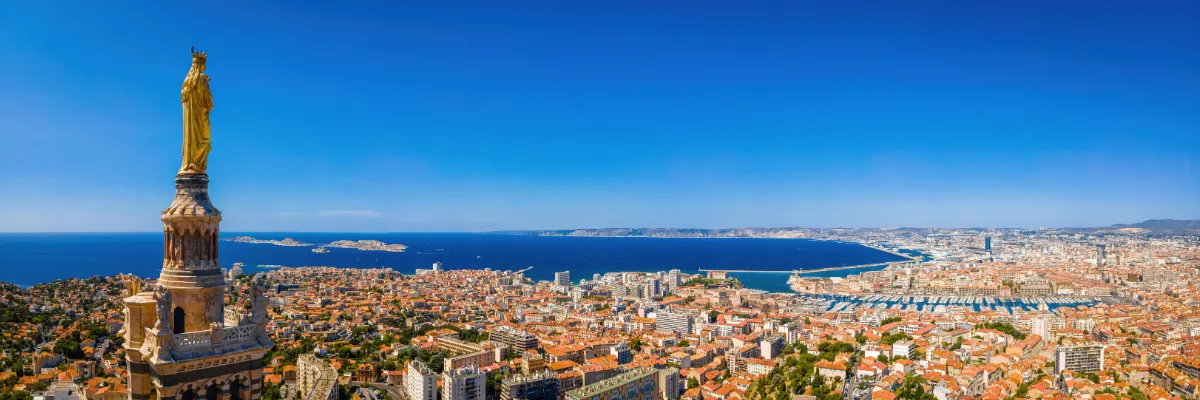 Blick von der Kathedrale Notre Dame de La Garde über Marseille. Rechts die goldene Marienstatue auf dem Glockenturm, im Hintergrund das Mittelmeer.