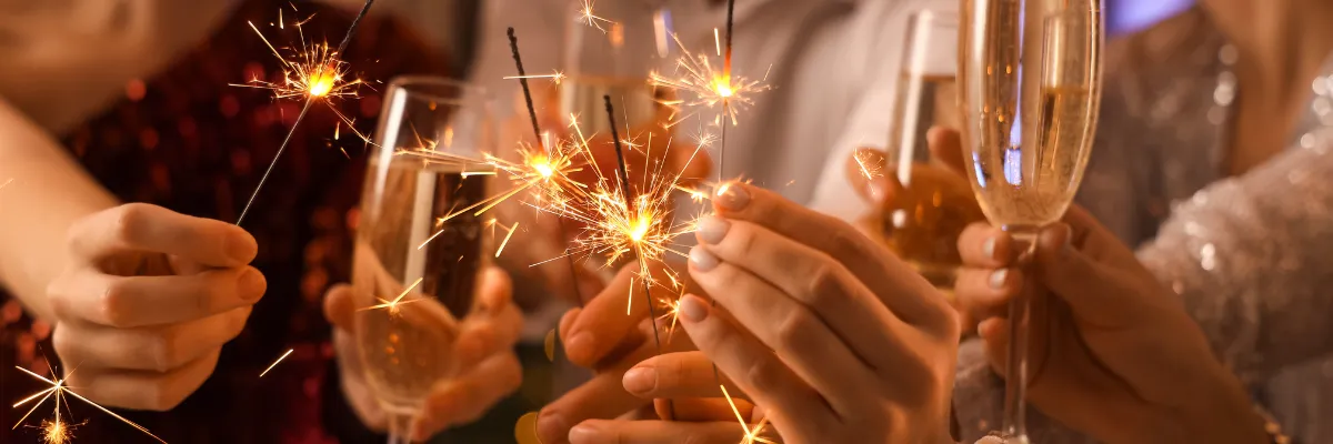 Compass Kreuzfahrten Silvester 2026 Eine Gruppe von Freunden feiert mit Champagner und Wunderkerzen Silvester auf einem Schiff von Compass Kreuzfahrten.