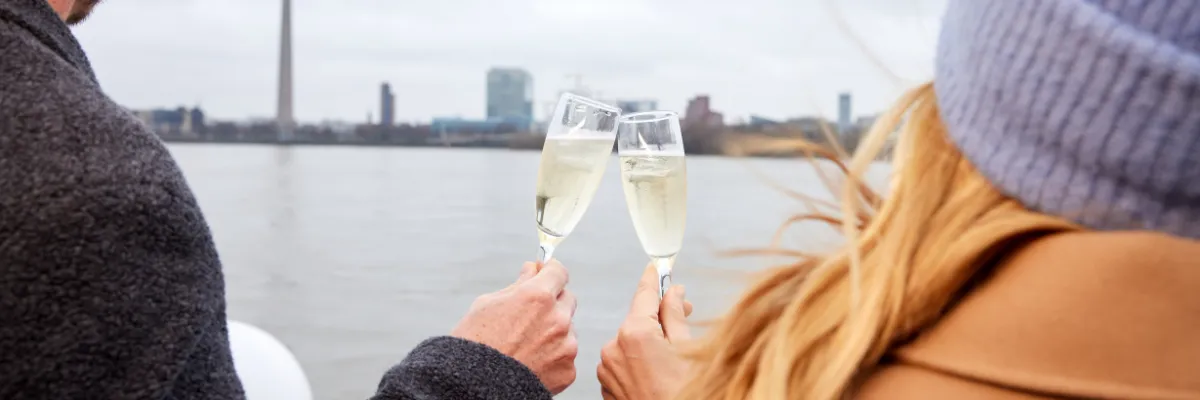 VIVA Cruises Silvester-Flusskreuzfahrt 2026 Ein Paar steht auf dem oberen Deck und stößt mit Sekt an. Sie werden abends Silvester auf dem Flusskreuzfahrtschiff in Düsseldorf feiern.