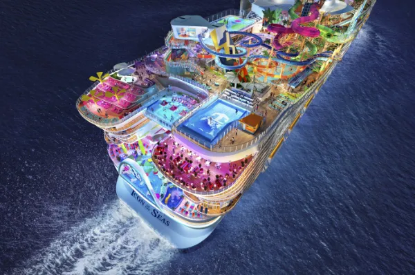 Nachts fährt das hell erleuchtete Schiff Icon of the Seas über das Wasser.