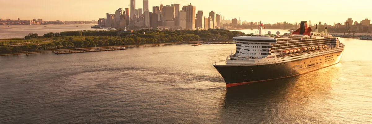 Transatlantik-Kreuzfahrt mit Cunard: Die Queen Mary 2 vor der Kulisse Manhattans in New York Die Queen Mary 2 von Cunard vor der Skyline von New York bei Sonnenuntergang – Der legendäre Ocean Liner auf Transatlantik-Kreuzfahrt.