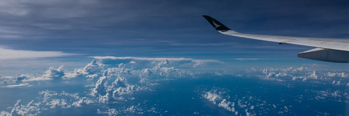 Komfortable An- und Abreise per Langstreckenflug über den Atlantik Blick aus dem Flugzeugfenster auf den Ozean und Wolken – An- und Abreise per Langstreckenflug bei Transatlantik-Kreuzfahrten.
