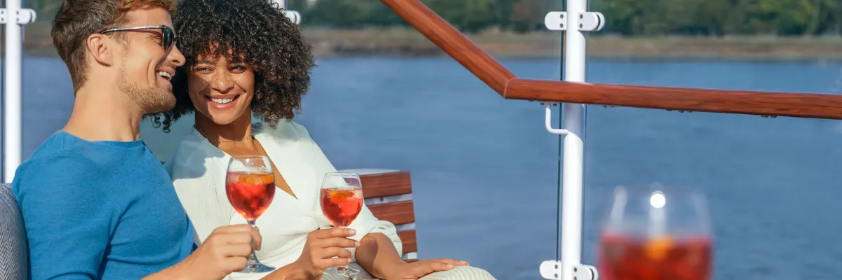 All Inclusive Flusskreuzfahrt Ein Pärchen genießt inklusive Aperol Spritz an Deck eines A-ROSA-Flussschiffs.