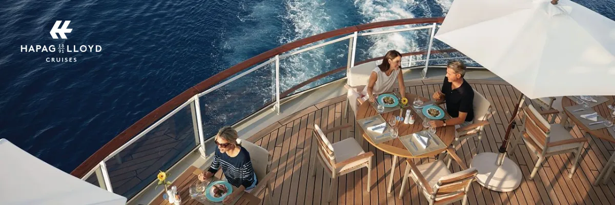 Einige Personen nehmen an Deck eines der luxuriösen Schiffe von Hapag-Lloyd ein leichtes Mittagessen ein.