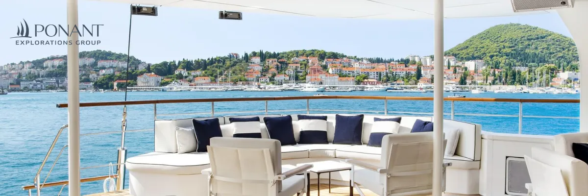 PONANT Segelkreuzfahrt buchen Das Sonnendeck auf Le Ponant mit bequemen Sitzmöbelnn und einer Aussicht auf die Stadt Dubrovnik in Kroatien.
