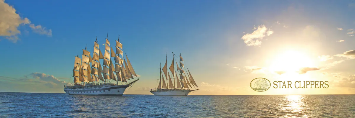 Star Clippers Segelkreuzfahrt buchen Die Schwesterschiffe Star Clipper und Star Flyer segeln im Sonnenuntergang auf dem offenen Meer.