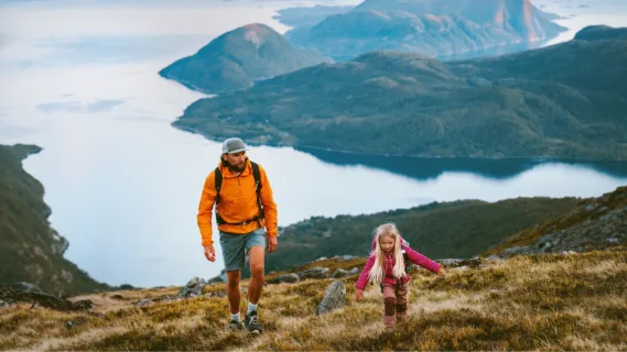 Ein Vater und seine Tochter wandern auf einem Berg auf den Kanaren und sind dabei von herbstlichem Grün umgeben.