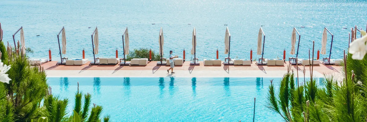 Sonnendeck mit Swimmingpool, Sonnenliegen und Panoramablick auf das offene Meer.