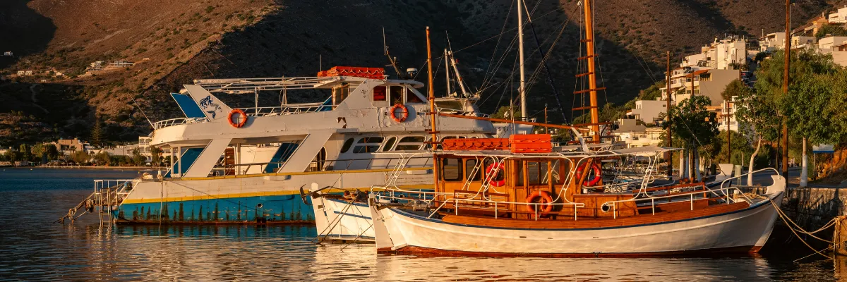 Traditionelle Fischerboote und Yachten im idyllischen Mittelmeer-Hafen bei Abendsonne.