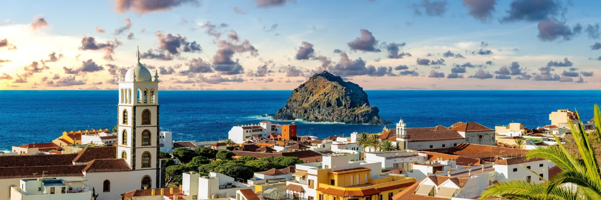Malerische Küstenstadt Garachico auf Teneriffa mit Kirchturm und dem Vulkanfelsen Roque de Garachico im Atlantik.