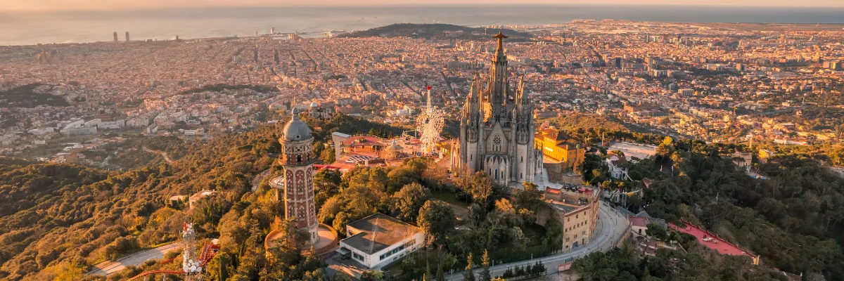 Westliches Mittelmeer Costa Frübucher 2027 2028 Eine alte Kirche auf einem Hügel und die Stadt Barcelona erstreckt sich am Fuße des Hügels in der Dämmerung.