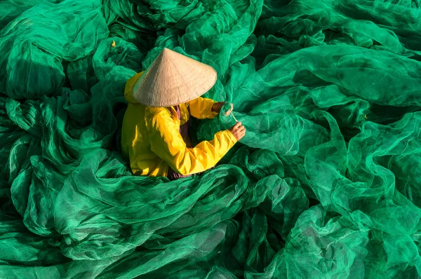 Mekongkreuzfahrt mit Scenic River Cruises Eine vietnamesische Frau sitzt inmitten von grünem Stoff.