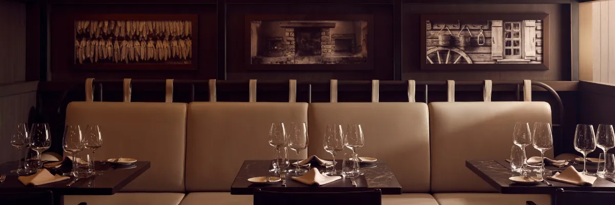 Elegante Sitzbank und eingedeckte Dinnertische im Restaurant Marble & Co. Grill an Bord von Explora Journeys.