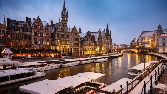 Winterliche Flusskreuzfahrt: Stimmungsvolle historische Grachtenkulisse im Schnee Verschneite historische Zunfthäuser an einer beleuchteten Gracht zur winterlichen Flusskreuzfahrt in der Abenddämmerung.