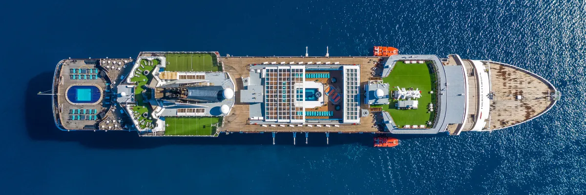 VASCO DA GAMA von nicko cruises aus der Vogelperspektive Spektakuläre Luftaufnahme des Kreuzfahrtschiffs VASCO DA GAMA mit Sonnendecks, Pools und weitläufigen Holzpromenaden auf tiefblauem Meer.