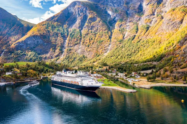 VASCO DA GAMA von nicko cruises in norwegischer Fjordkulisse Das klassische Hochseekreuzfahrtschiff VASCO DA GAMA von nicko cruises liegt im ruhigen Fjordwasser vor einer malerischen Dorfkulisse und steil aufragenden Berghängen.