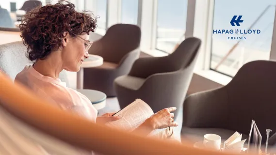 Angebote für Einzelreisende Eine Frau reist alleine auf einer Hapag-Lloyd Kreuzfahrt und liest in Ruhe ein Buch an Bord.