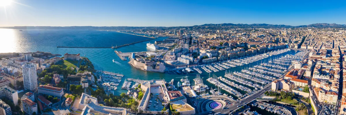 Jetzt Mittelmeerkreuzfahrt mit reduziertem Getränkepaket sichern! Blick über den Hafen von Marseille mit dem Yachthafen im Vordergrund und dem Kreuzfahrthafen im Hintergrund.