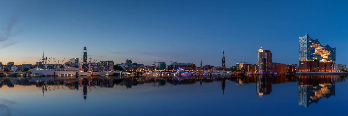 Entdecken Sie die Metropolen Euruopas mit Getränkevorteil Panoramablick des abendlichen Hamburger Hafens mit der Elbphilharmonie am rechten Bildrand.