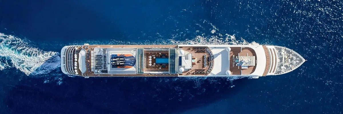 Hapag-Lloyd Cruises Luxusschiff: Vogelperspektive auf das Oberdeck der EUROPA 2 Spektakuläre Luftaufnahme im steilen Winkel von oben auf das Sonnendeck und den Poolbereich der EUROPA 2, die mit eleganter Bugwelle durch das tiefblaue Meer gleitet.
