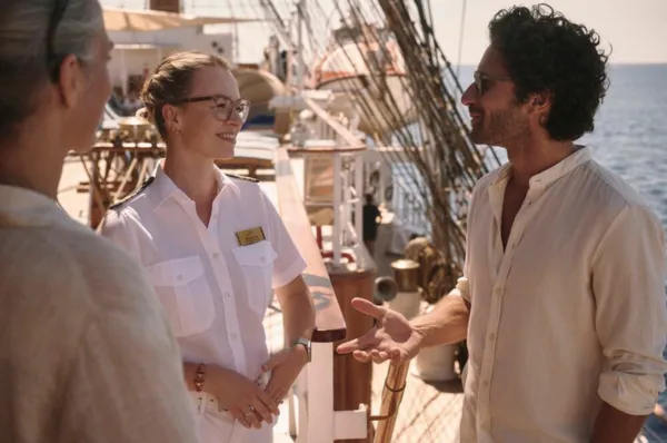 Gäste sprechen mit einer Servicemitarbeiterin an Bord eines Segelschiffes von Sea Cloud Cruises.