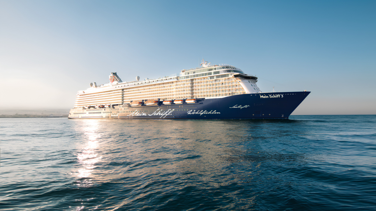 Das Kreuzfahrtschiff Mein Schiff 3 von TUI Cruises fährt bei sonnigem Wetter und ruhiger See auf dem offenen Meer.