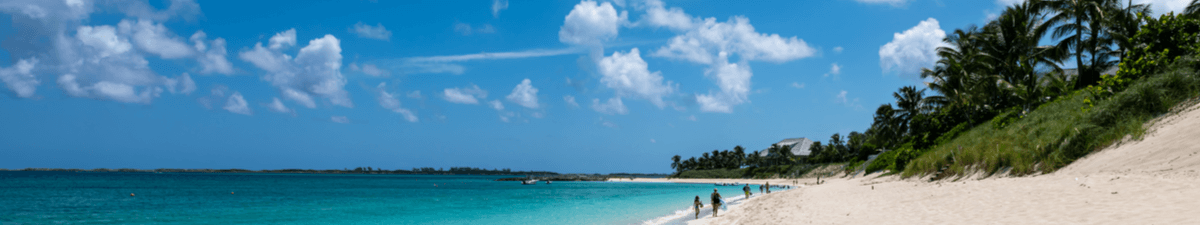 Cabbage Beach auf den Bahamas mit weißem Sand, hellblauem Wasser und Palmen.
