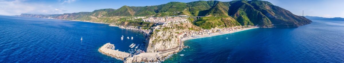 Panoramasicht auf die Hafenstadt Tropea mit grünen Bergen im Hintergrund.