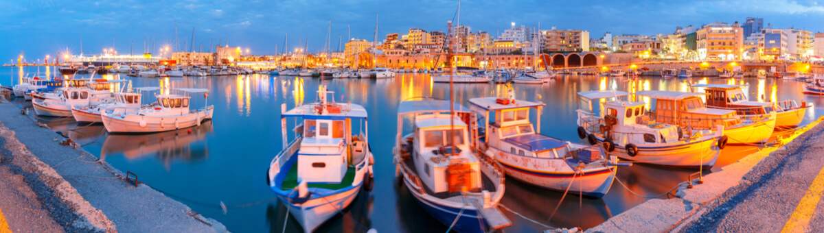 In der Dämmerrung sehen Sie kleine Boote un Schiffe erleuchtet im Hafen Heraklion